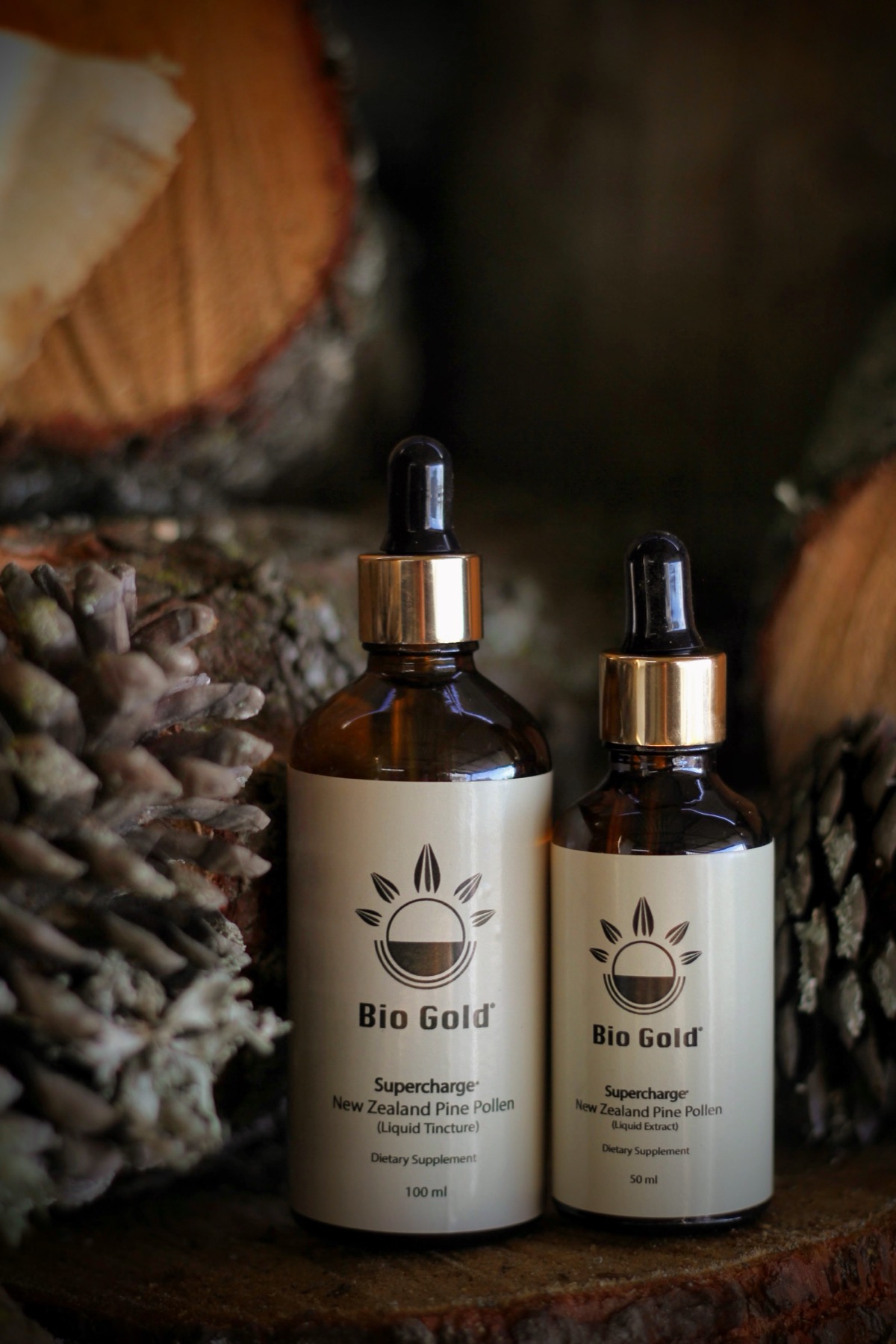 Biogold pine pollen tincture bottles among pine cones and cut wood